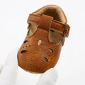 Close view of a brown baby T-strap shoe with cut-out sides