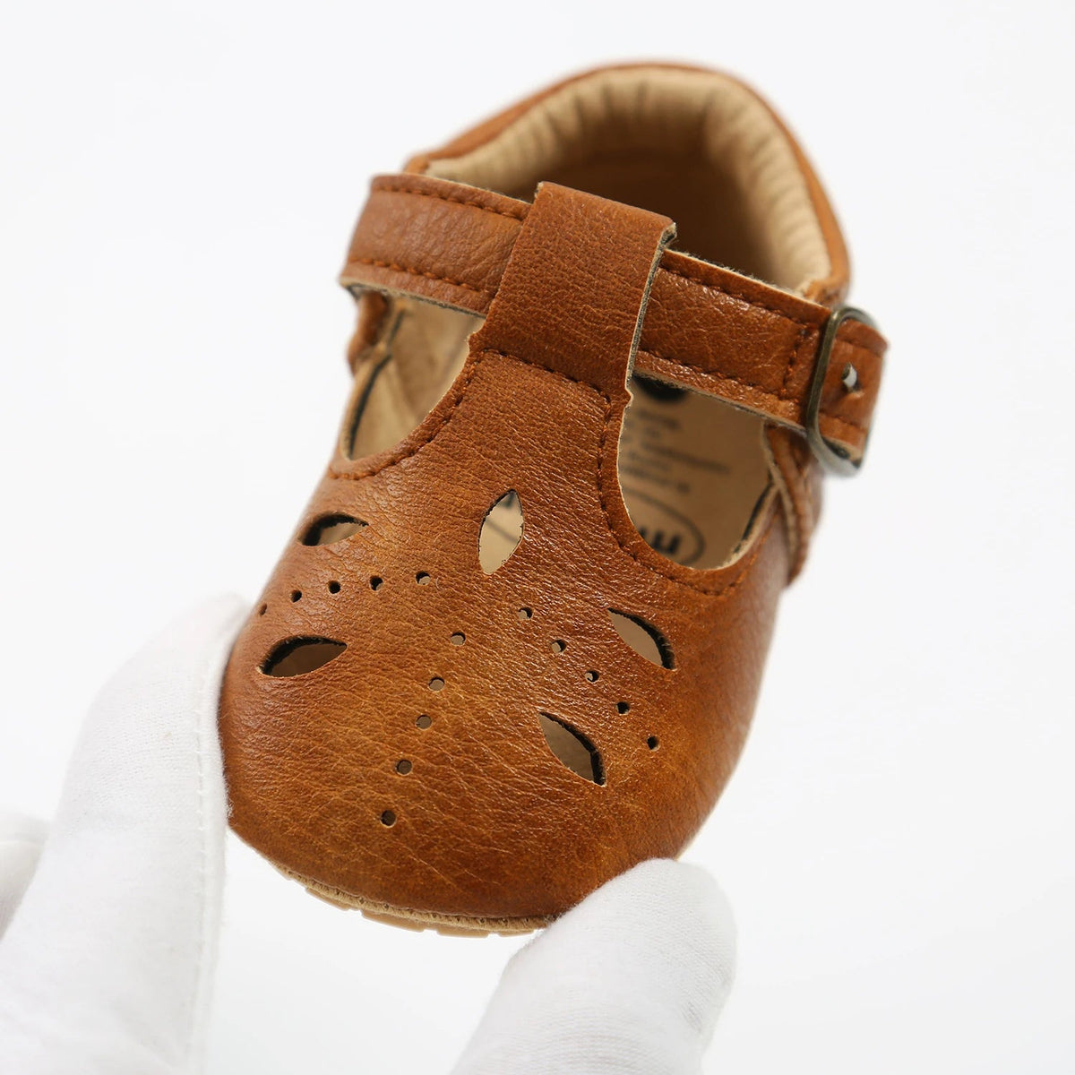Close view of a brown baby T-strap shoe with cut-out sides