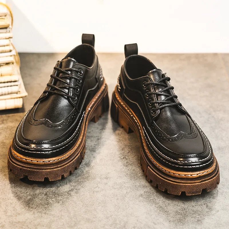 Pair of black lace-up brogue-style shoes with thick brown lug soles on a grey carpet