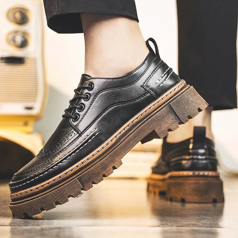 Black lace-up brogue-style shoe with a thick brown lug sole worn from the side with black trousers