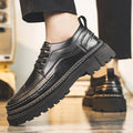 Black lace-up brogue-style shoe with a thick black lug sole worn from the side with black trousers