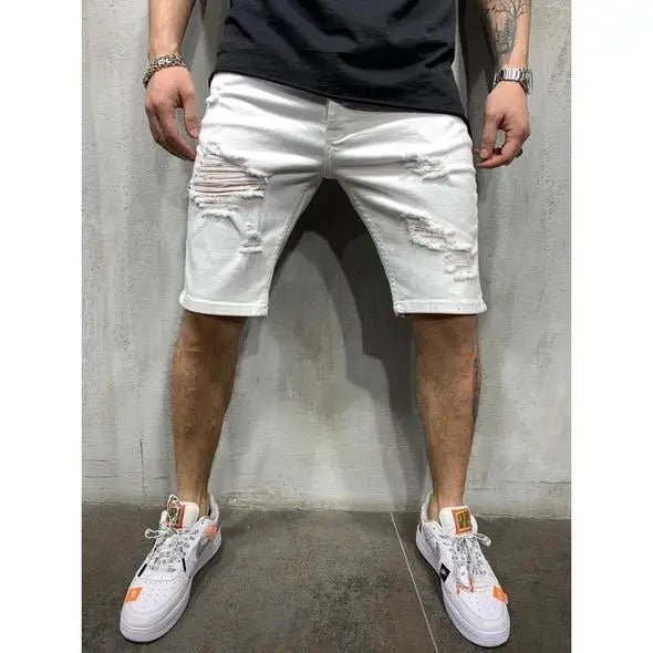 Men's white distressed denim shorts with ripped details, worn with a dark t-shirt and white sneakers