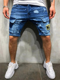Men's dark blue distressed denim cargo shorts with a side pocket and small embroidered patches, worn with white sneakers