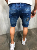Men's dark blue distressed denim shorts worn from behind, with paint-splatter marks and a back pocket