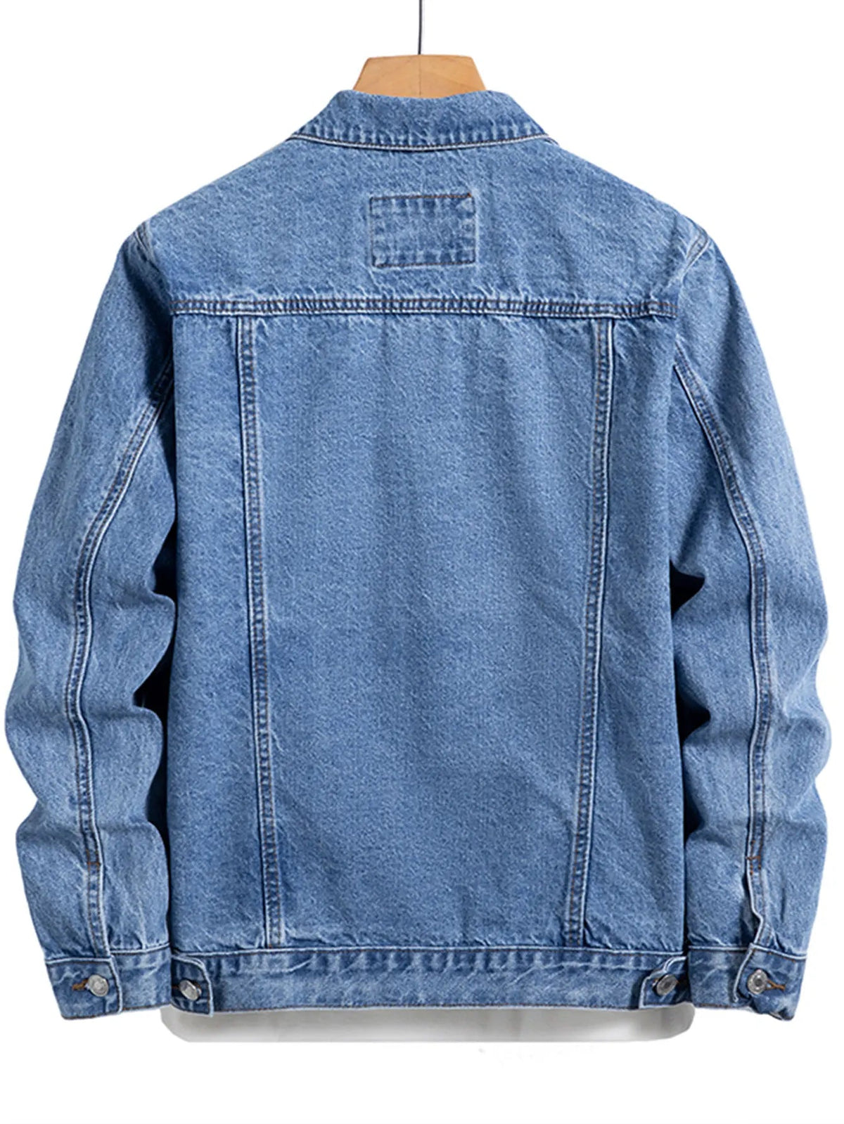 Back of a blue denim jacket on a wooden hanger, showing seam lines across the yoke