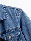 Close-up of a blue denim jacket shoulder, collar and buttoned chest pocket