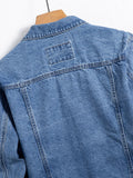 Close-up of the back yoke of a denim jacket showing a small woven patch