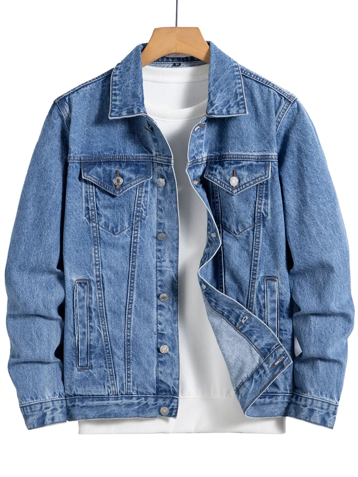 Blue denim jacket with a button front and chest flap pockets, hanging on a wooden hanger