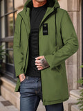 Man in a green mid-length hooded zip jacket with a small tag, standing on a city street