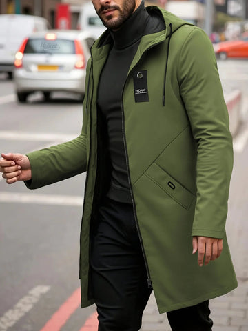 Man in a green hooded zip jacket and black top walking along a city street