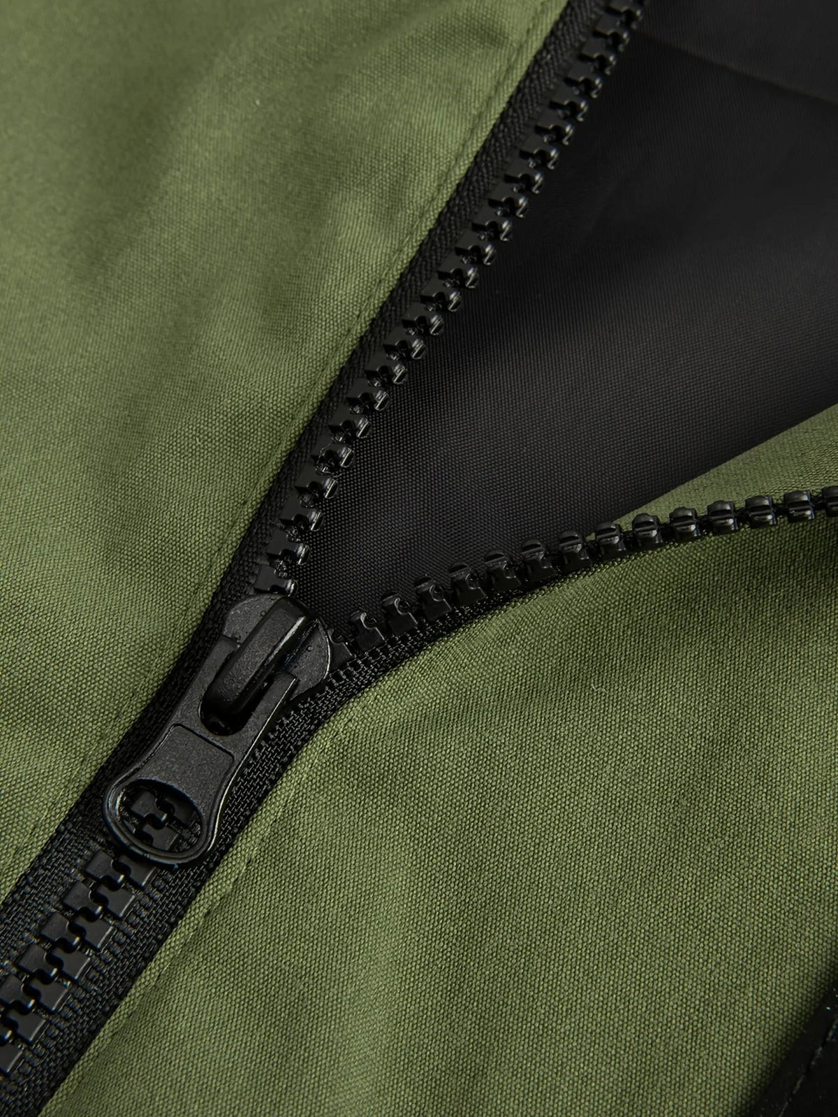 Close-up of a black zip with a silver pull on a green jacket
