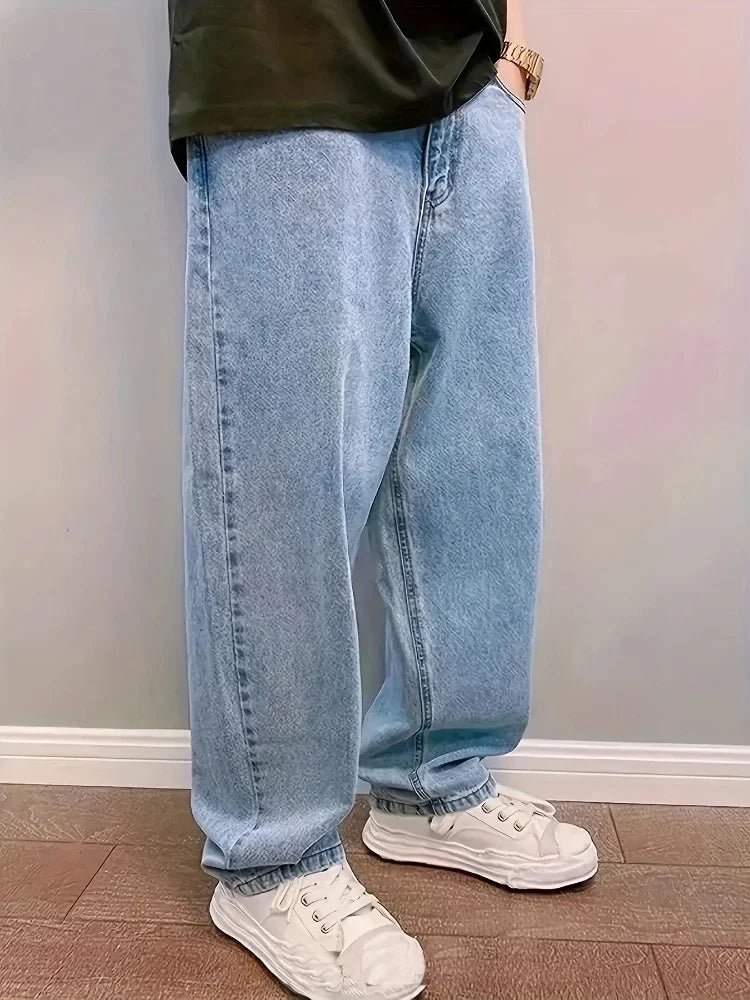 Side view of light blue baggy wide-leg jeans worn with white sneakers on a wooden floor