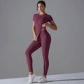 Woman in a burgundy short-sleeve top and matching leggings with one hand at the waist