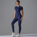 Woman in a navy blue short-sleeve top and matching leggings with one hand at the waist