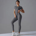 Woman in a dark grey short-sleeve top and matching leggings with one hand at the waist