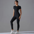 Woman in a black short-sleeve top and matching leggings with one hand at the waist