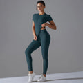 Woman in a dark teal green short-sleeve top and matching leggings with one hand at the waist