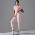 Woman in a light pink short-sleeve top and matching leggings with one hand at the waist