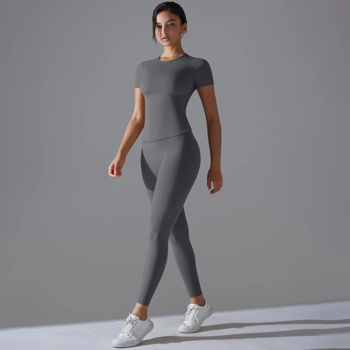 Woman in a grey short-sleeve fitted top and matching full-length leggings, three-quarter view