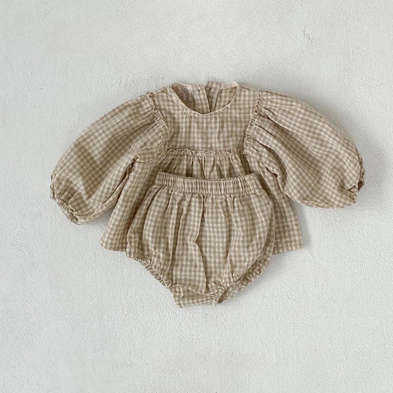 Beige gingham baby top with puff sleeves and matching bloomers laid flat