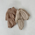 Apricot and beige gingham baby outfits laid flat together