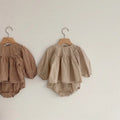 Apricot and beige gingham baby tops with puff sleeves on wooden hangers