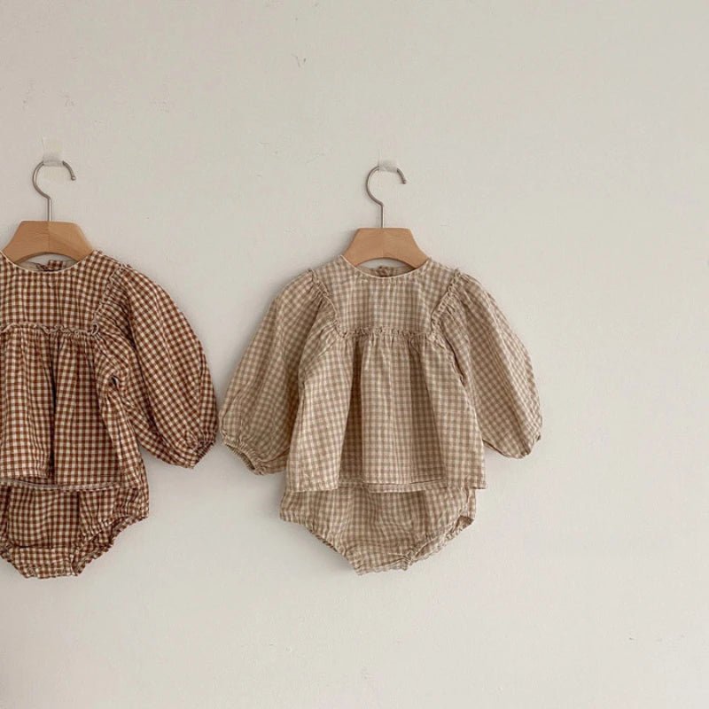 Apricot and beige gingham baby tops with puff sleeves on wooden hangers