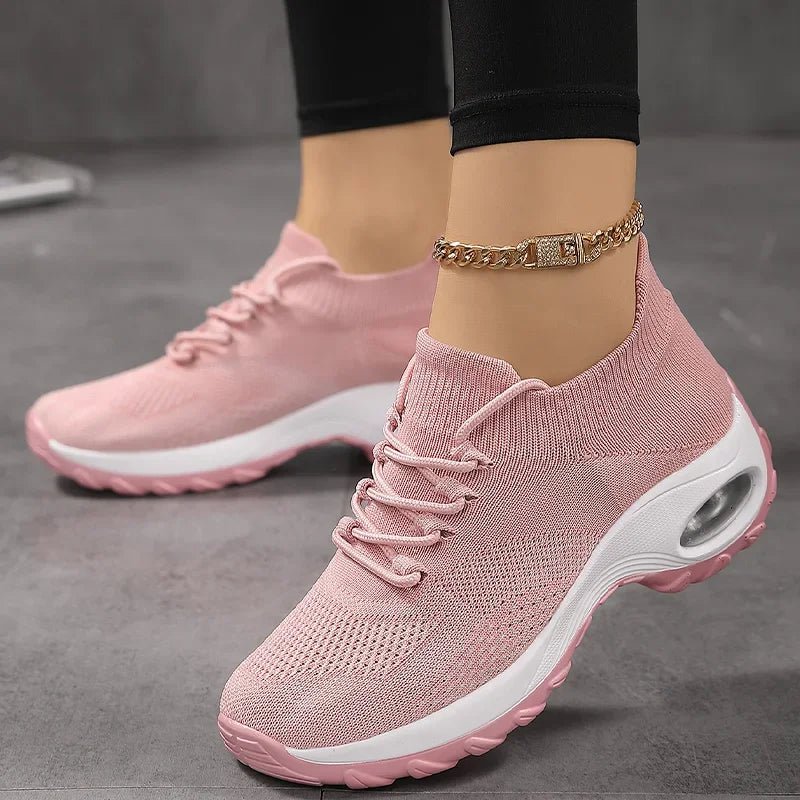 Pink knit slip-on sneakers with laces and a thick white cushioned sole, worn with an ankle chain