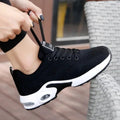 Woman tying the laces of a black knit sneaker with a white air-cushion sole
