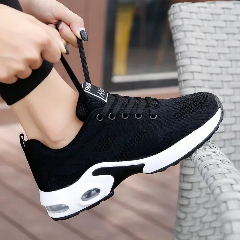 Woman tying the laces of a black knit sneaker with a white air-cushion sole