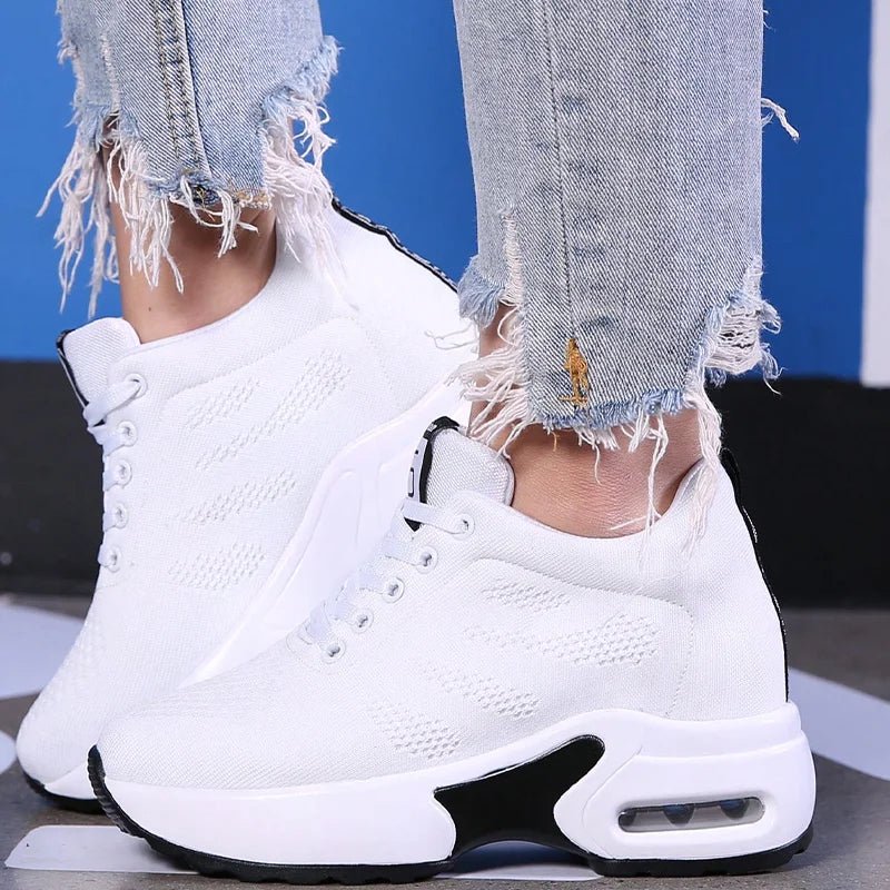 White high-top style lace-up sneakers with a visible air-sole heel, worn with ripped jeans