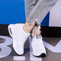 White air-sole sneakers seen from the side with a visible window in the heel and ripped jeans above