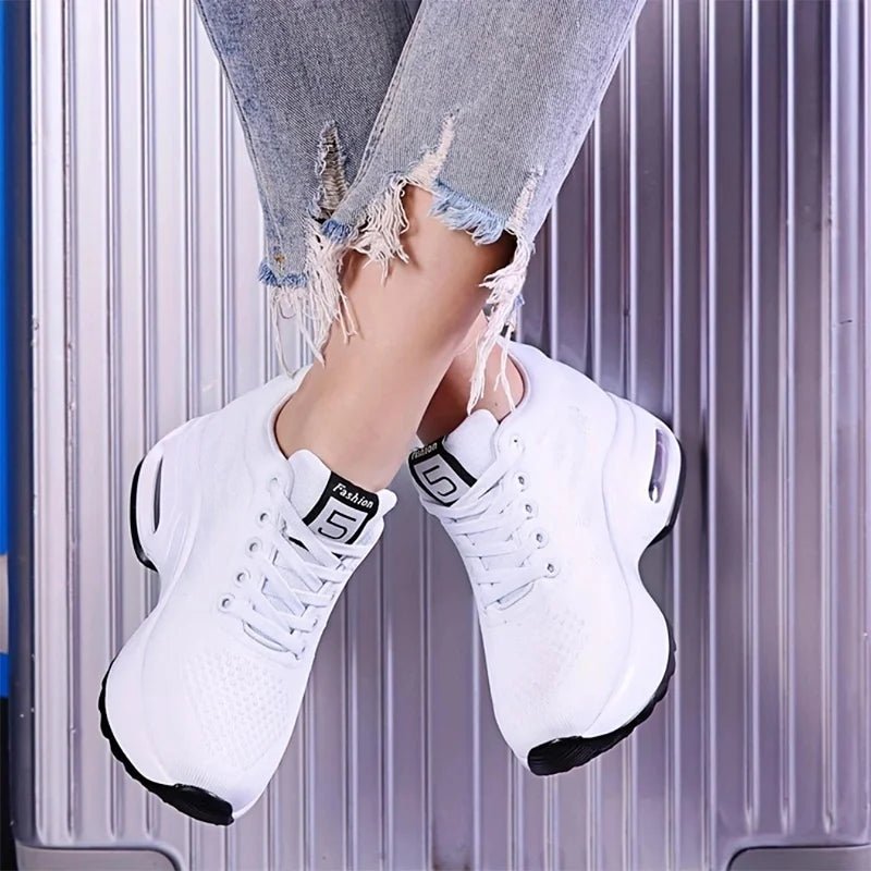 White lace-up sneakers with a small square tongue label and thick sole, worn with ripped jeans