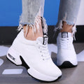 White lace-up sneakers with a raised cushioned sole worn with ripped jeans, three-quarter view