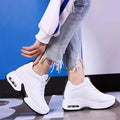 Two white lace-up sneakers with thick soles worn with frayed jeans, front view