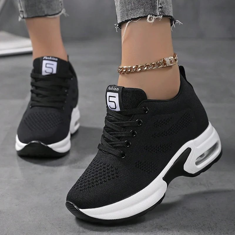 Black knit lace-up sneakers with a thick white sole and ankle chain, front view