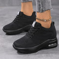 Pure black lace-up sneakers with a thick cushioned sole, worn with an ankle chain