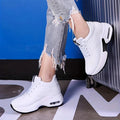 Pair of white platform sneakers with black sole accents worn with ripped jeans, standing view