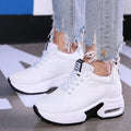 White platform air-sole sneakers worn with ripped jeans, side view showing the lace-up front and cushioned sole