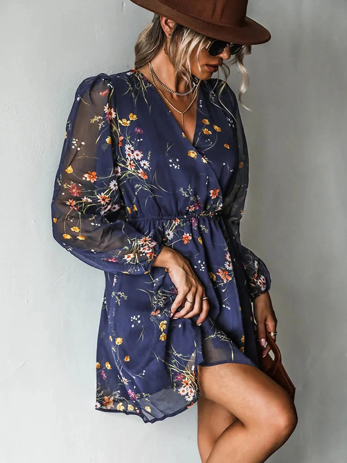 Navy mini dress with small flower print, V-neckline and sheer cuffed sleeves, worn with a brown hat