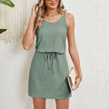 Woman in a sage green sleeveless mini dress with a drawstring waist, green colour option