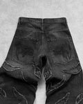 Close-up of black washed baggy jeans with frayed thread lines on the legs